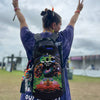 Festival attendee wearing a Lunchbox hydration backpack featuring the EDC Orlando 2026 skin while throwing up peace signs