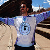 Man wearing sunglasses and a limited edition white and lavender Lunchbox festival hockey jersey outdoors at Red Rocks amphitheater.