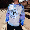 Front view of man wearing limited edition white and lavender Lunchbox festival hockey jersey outdoors at Red Rocks amphitheater.