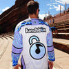 Back view of man wearing limited edition white and lavender Lunchbox festival hockey jersey outdoors at Red Rocks amphitheater.