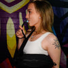 Side profile of a person drinking from the hydration hose of the black Lunchbox Hydration Sling.
