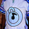 Close-up detail of embroidered circular padlock icon with music note on limited edition Lunchbox festival baseball jersey.