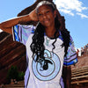 Woman wearing limited edition white and purple Lunchbox festival baseball jersey outdoors at Red Rocks amphitheater.