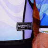 Close-up detail of woven Lunchbox Packs EST. 2017 brand tag on lower hem of limited edition festival hockey jersey.