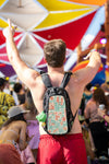 Man with arms raised wearing a Lollapalooza 2026 hydration pack with colorful Chicago line art skin at a crowded festival