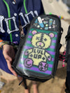 A person holding a black Lunchbox hydration pack featuring the "Pin Skin" with a custom-made Perler bead bear display, featuring "LVL UP" text and a purple and green striped background protected behind a clear shell.
