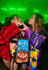 Two ravers in colorful outfits making a heart shape with their hands in front of a Lunchbox pack featuring the 